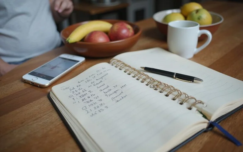 Notebook and phone recording dated observations about doors and cracks in a house