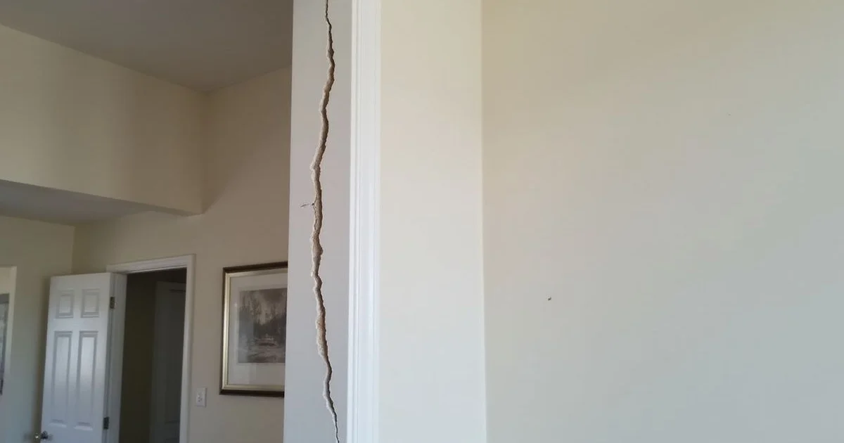 Diagonal crack running from the upper corner of a door frame across an interior painted wall